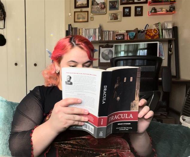 Image of a person with pink hair reading